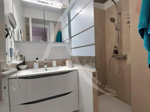 une salle de bain blanche avec un lavabo et une douche dans l'établissement T2 sur zone pietonne, a quelques pas des plages, à Sète