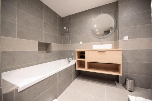 une salle de bain avec une baignoire, un lavabo et un miroir dans l'établissement CIA - Les Halles-Rivoli 6P, à Paris