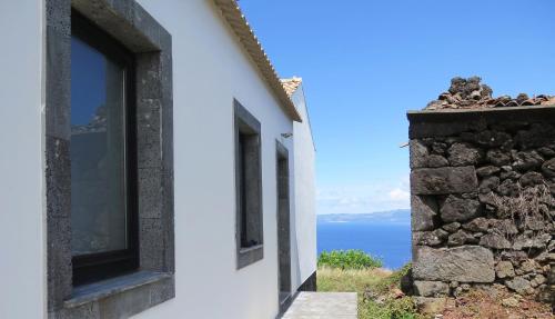 a window on the side of a building with a view of the ocean at Areias da Prainha in Prainha de Cima