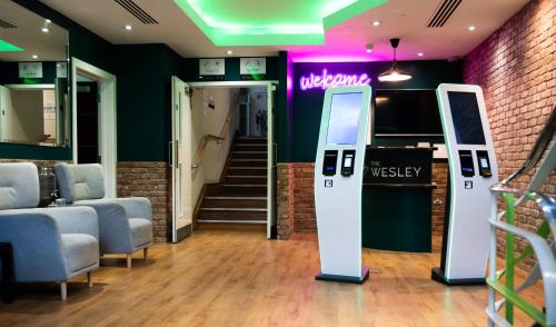 a waiting room with a welcome sign and chairs at The Wesley Euston in London