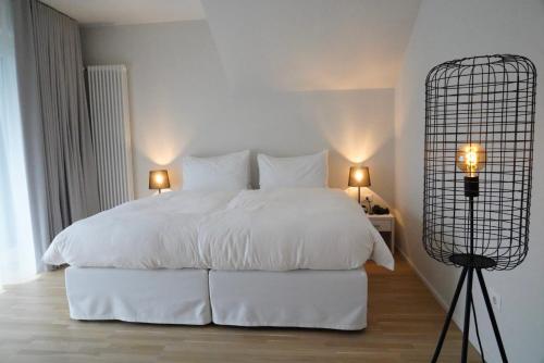 a bedroom with a large white bed with two lamps at Design Hotel Tyrol in Rablà