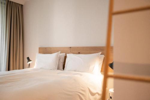 a bedroom with a bed with white sheets and pillows at Design Hotel Tyrol in Rablà