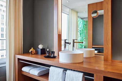 a bathroom with two sinks and a mirror at Me and All Hotel Dusseldorf, by Hyatt in Düsseldorf