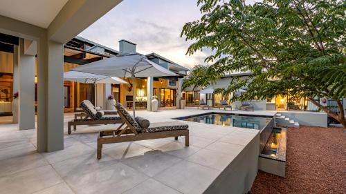 a house with a pool and two chairs and an umbrella at Ingwenkala Luxury Safari Lodge in Hoedspruit