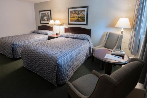 a hotel room with two beds and a table and chairs at Grama's Inn in Prince George