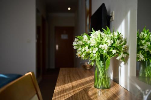 a vase of white flowers sitting on a table at Hotel Phoenix in Velika Gorica