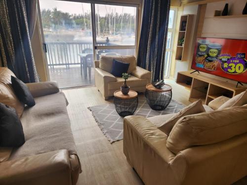 a living room with two couches and a balcony at Hillton Manor Guest House in Richards Bay