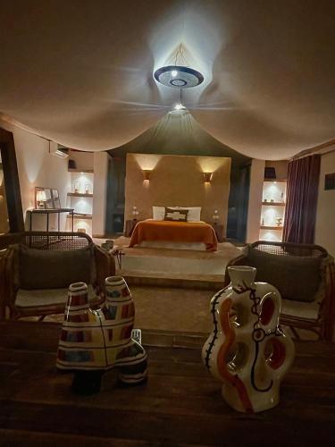 a bedroom with a bed and a room with vases at Manzil La Tortue in Douar Caïd Layadi