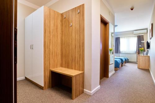 a room with a wooden cabinet and a bench at Hotel Phoenix in Velika Gorica