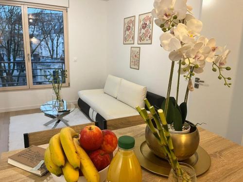 une table avec un bol de fruits et un vase de fleurs dans l'établissement Seemingly Spacious Modern & Bright Chic Paris, à Paris