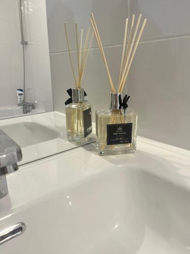deux bouteilles de parfum posées sur un lavabo de salle de bain dans l'établissement Seemingly Spacious Modern & Bright Chic Paris, à Paris