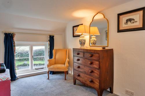 a bedroom with a dresser and a chair and a mirror at Finest Retreats - Whitley in Molland