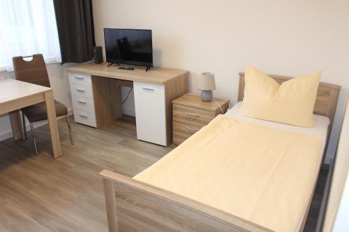 a bedroom with a bed and a desk with a television at Vario Gästehaus in Greifswald
