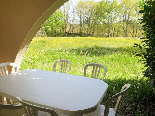 une table et des chaises blanches dans un champ d'herbe dans l'établissement Apartment Le Domaine de Claire Rive-2 by Interhome, à Prayssac