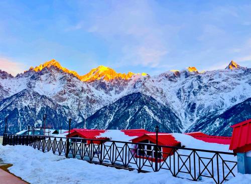 a snowy mountain range with red roofs and snow covered mountains at Hotel Rollingrang in Kalpa