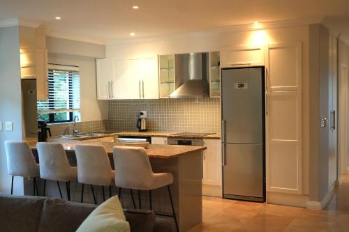 a kitchen with white cabinets and a island with bar stools at Pearl Valley family golf lodge on nature lake with mountain views in Simondium