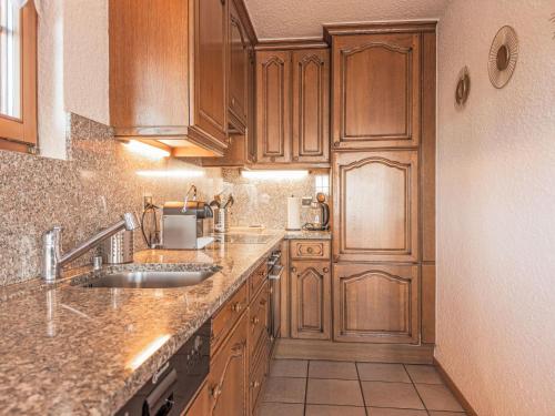 a kitchen with wooden cabinets and a sink at Holiday Home Echo du Mihi by Interhome in Nendaz
