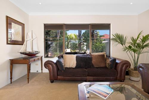 a living room with a brown couch and a table at Cronulla Beach House B&B in Cronulla