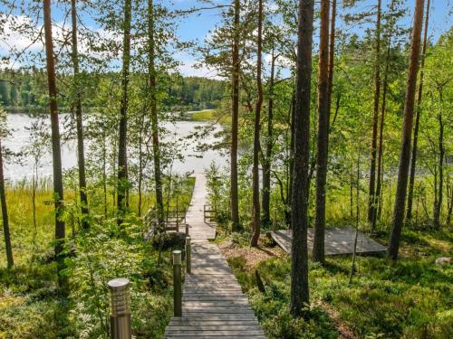 een houten pad door een bos naast een meer bij Holiday Home Karhupirtti by Interhome in Mäntyharju