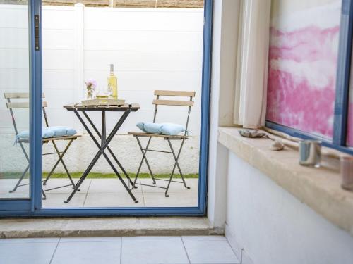 - une table et des chaises assises sur une terrasse couverte à côté d'une fenêtre dans l'établissement Holiday Home La Plagette by Interhome, à Aigues-Mortes