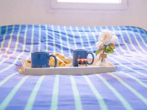 - un plateau avec deux tasses et une assiette de nourriture sur un lit dans l'établissement Holiday Home La Plagette by Interhome, à Aigues-Mortes