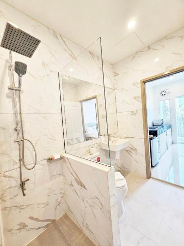 a white bathroom with a toilet and a shower at Mercy Hostel in Chiang Rai