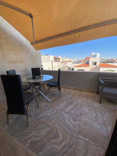 a balcony with a table and chairs and a couch at abdoun rooftop 1bedroom kh&sh 04 in Amman