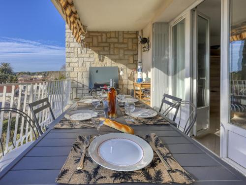 une table avec des assiettes et des verres à vin sur un balcon dans l'établissement Apartment Les Palmiers-4 by Interhome, à Saint-Cyr-sur-Mer