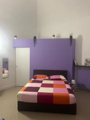 a bedroom with a colorful bed with a purple wall at Angolo di Viola in Turin