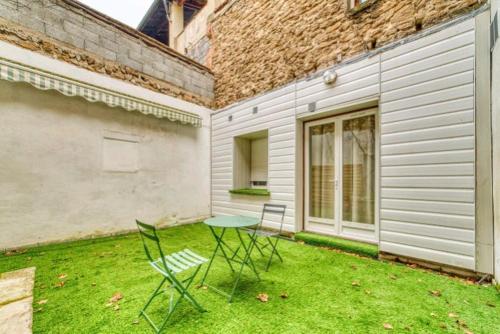 une table et des chaises assises dans l'herbe dans une cour dans l'établissement Charme en Ville, à Romans-sur-Isère