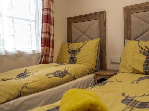 a bedroom with two beds with yellow comforters at Chalet Monarch by Interhome in Aviemore