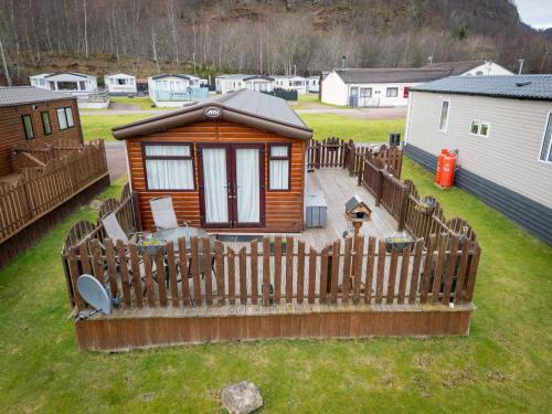 a small cabin with a wooden fence in a yard at Chalet Monarch by Interhome in Aviemore