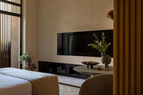 a room with a tv and a bed and a table at The Newel Psychiko in Athens