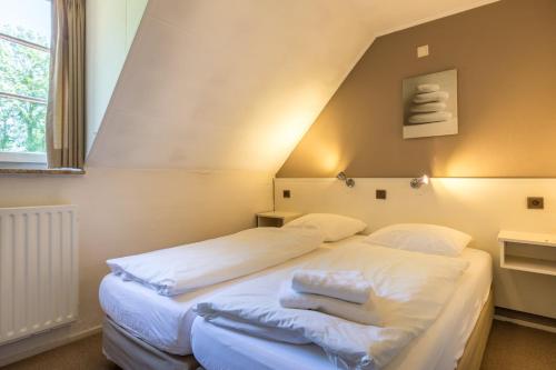 a bed with white sheets and pillows in a room at Herberg de Geulhemermolen in Berg en Terblijt