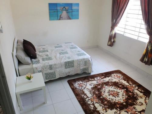 a bedroom with a bed and a table and a rug at Dillenia Nilai Homestay in Nilai