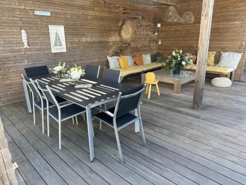 une table et des chaises sur une terrasse avec un canapé dans l'établissement Maison La Julise, Piscine & Mer, au Croisic