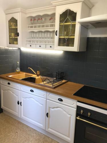 une cuisine avec des armoires blanches et un évier dans l'établissement La Théresand, à Pontevès