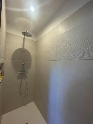 La salle de bains est pourvue d'une douche avec une lumière sur le mur. dans l'établissement Maison La Julise, Piscine & Mer, au Croisic