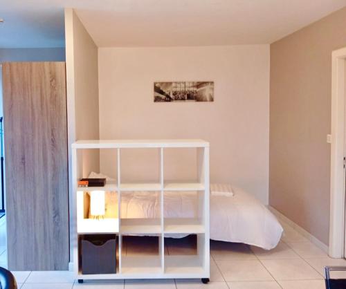 - une chambre avec un lit et une étagère blanche dans l'établissement Charmant studio à Montbéliard, à Montbéliard