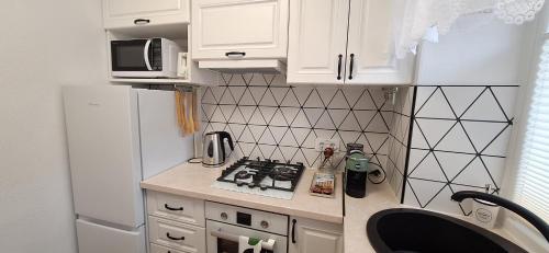 a small kitchen with white cabinets and a white refrigerator at Šiauliai Central Vytauto Apartment in Šiauliai