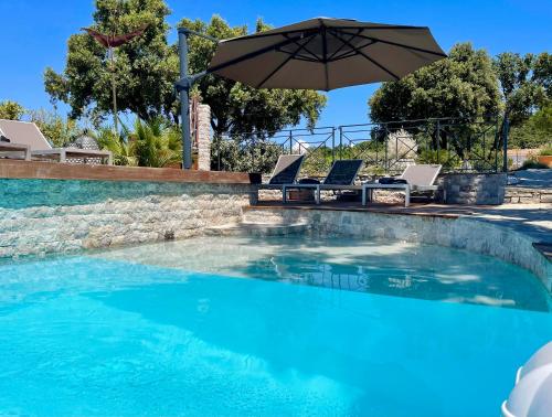 - une piscine avec un parasol et des chaises dans l'établissement Maison dans les Arbres PISCINE CLIM Luxe, à Hyères