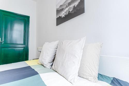 a bed with white pillows and a green door at Lovely & Comfortable Studio Apartments at Heart of Gent in Ghent