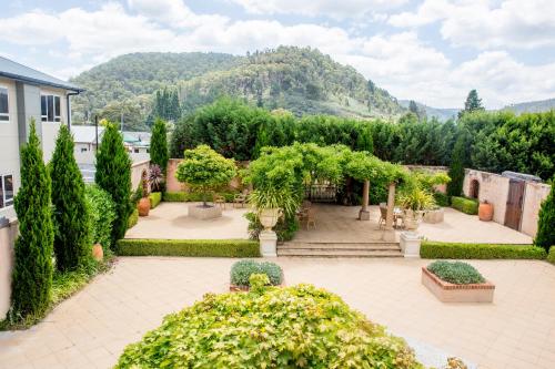 un giardino con alberi e cespugli e un edificio di Lithgow Workies Club Motel a Lithgow