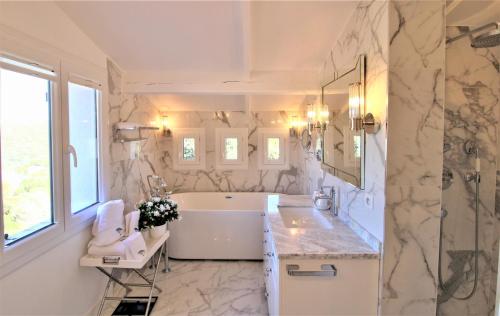 une salle de bain blanche avec une baignoire et un lavabo dans l'établissement Maison dans les Arbres PISCINE CLIM Luxe, à Hyères