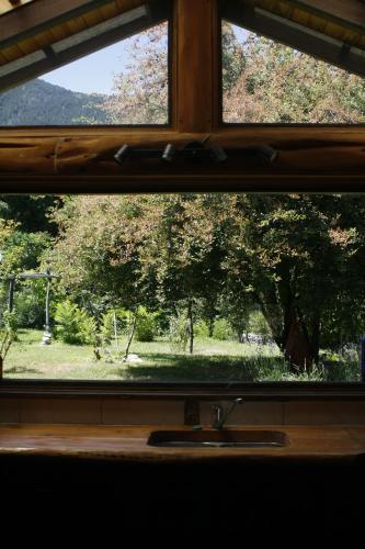 a window with a view of a park seen through it at Quinta Armonía Cabaña in Lago Puelo