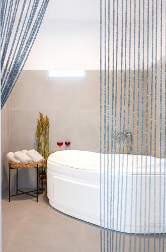 a bathroom with a tub and a shower curtain at Noho Villas @ Sunlit house Paros in Nea Cryssi Akti