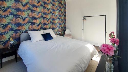 - une chambre avec un lit blanc et un mur coloré dans l'établissement Charmant studio, à Caen