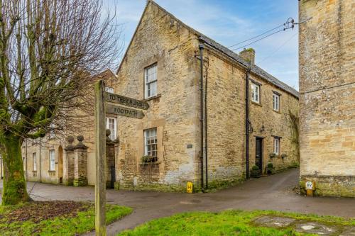 an old stone building with a street sign in front of it at Antelope Cottage in Northleach