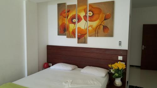 a bedroom with a bed with two paintings on the wall at The Den Guest House in Hikkaduwa