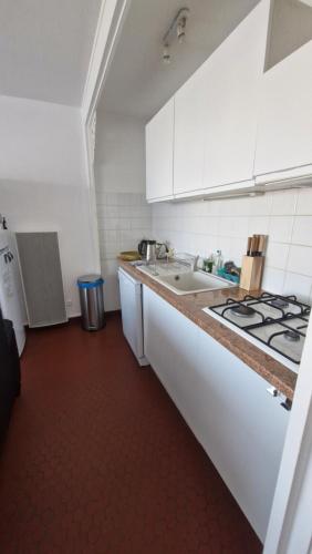 une cuisine blanche avec un évier et une cuisinière dans l'établissement RESIDENCE DU SOLEIL Spacieux T3 face à la mer au port - Parking, à Saint-Cyprien